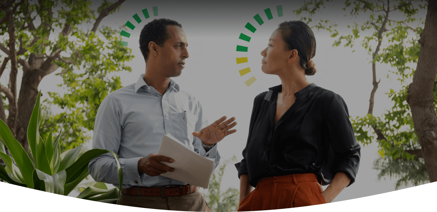 Coworkers walking outside while discussing some paperwork. One person has a D DiSC style halo and the other has a DC DiSC style halo.