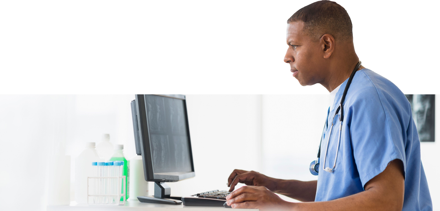 Person wearing medical scrubs working on a computer.