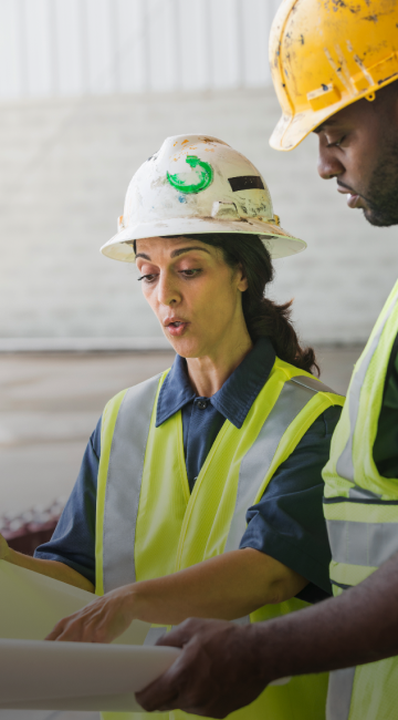Close-up of two people reviewing plans while working at a construction site.